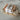 Orange bars of soap with a white label on top of a wooden soap dish and soap saver bag with a white label, all on a marble surface.