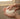 Person holding a bar of rose and neroli hair conditioner under running water