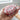 Hand holding a red foamy shampoo bar with a blurred bathroom background